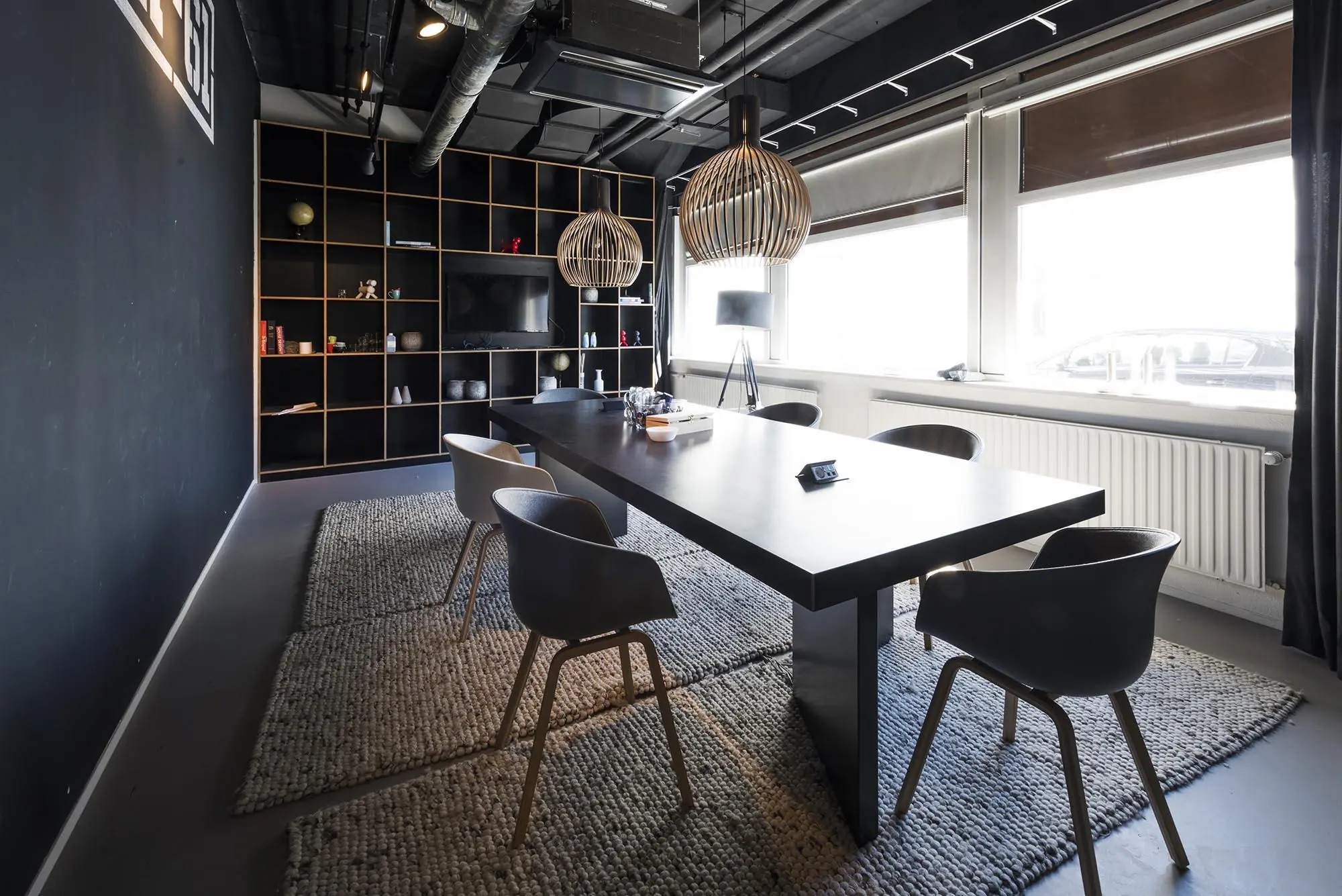 Moderne vergaderruimte aan de Anthony Fokkerweg met een zwarte tafel, designstoelen, wandkasten en grote ramen.